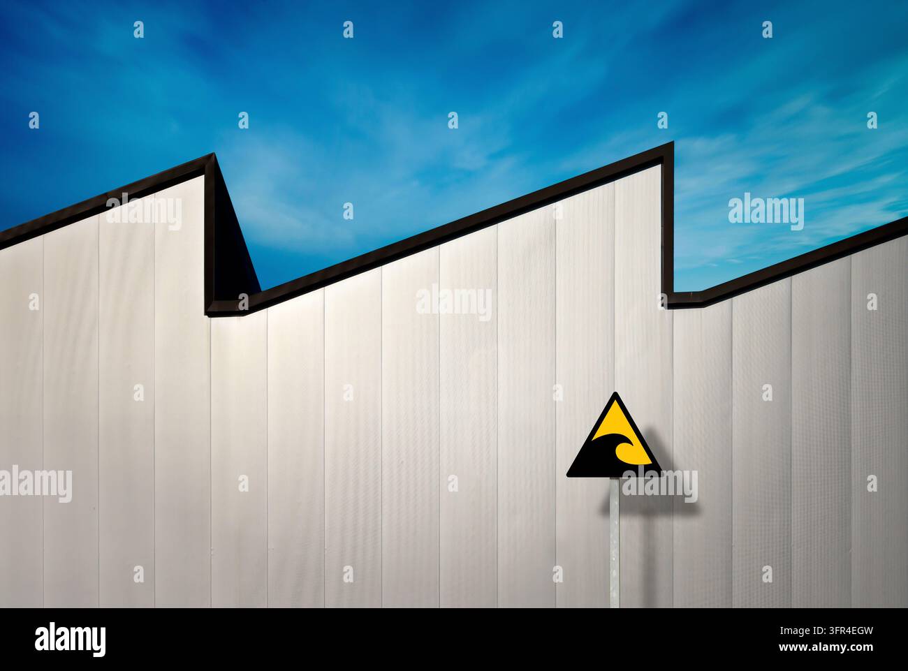 Composition of a wave-shaped façade that aligns with a wavy pattern in a blue sky. Stock Photo