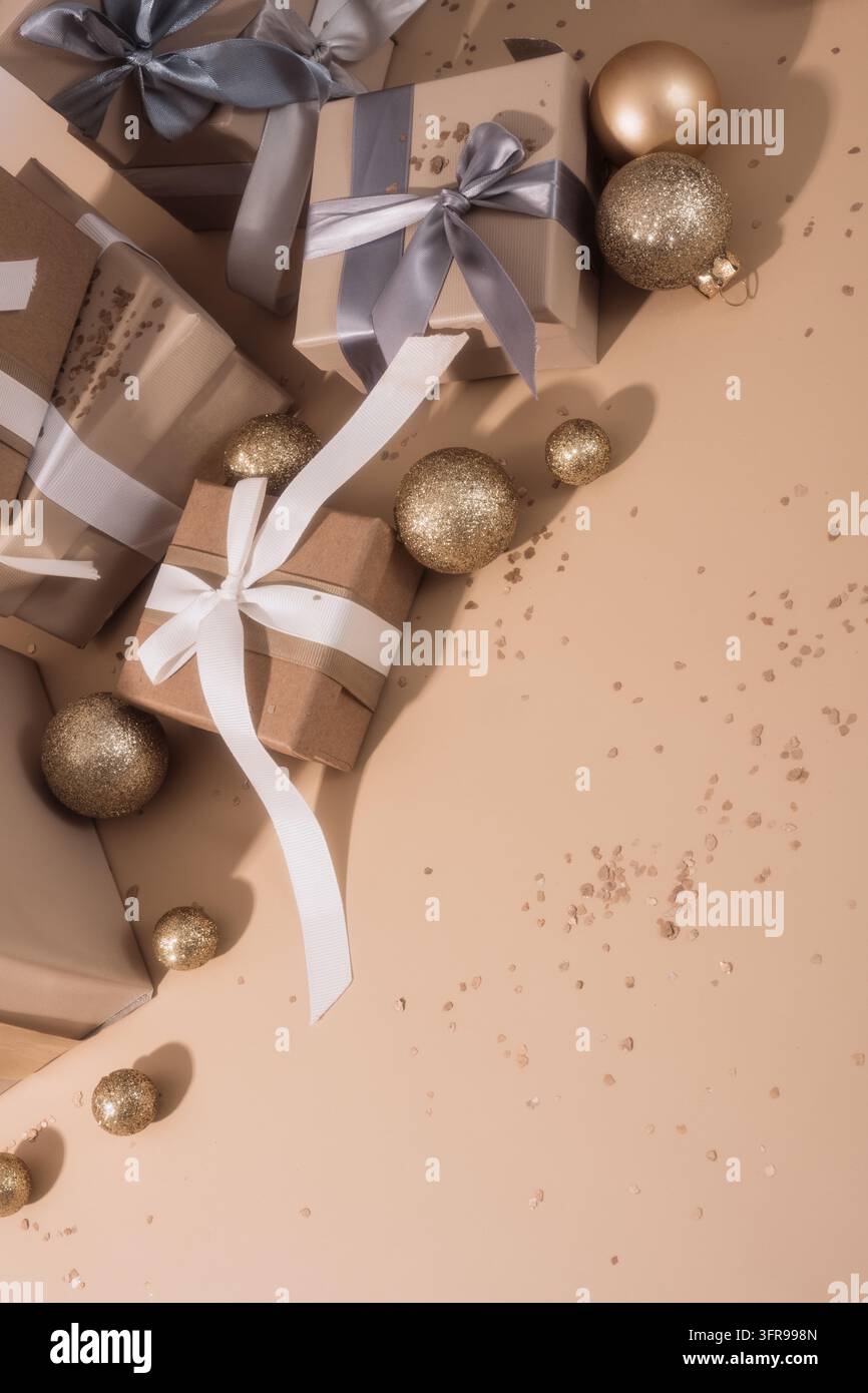 Brown gift boxes, ribbons and gold baubles arranged around beige empty space. Stock Photo