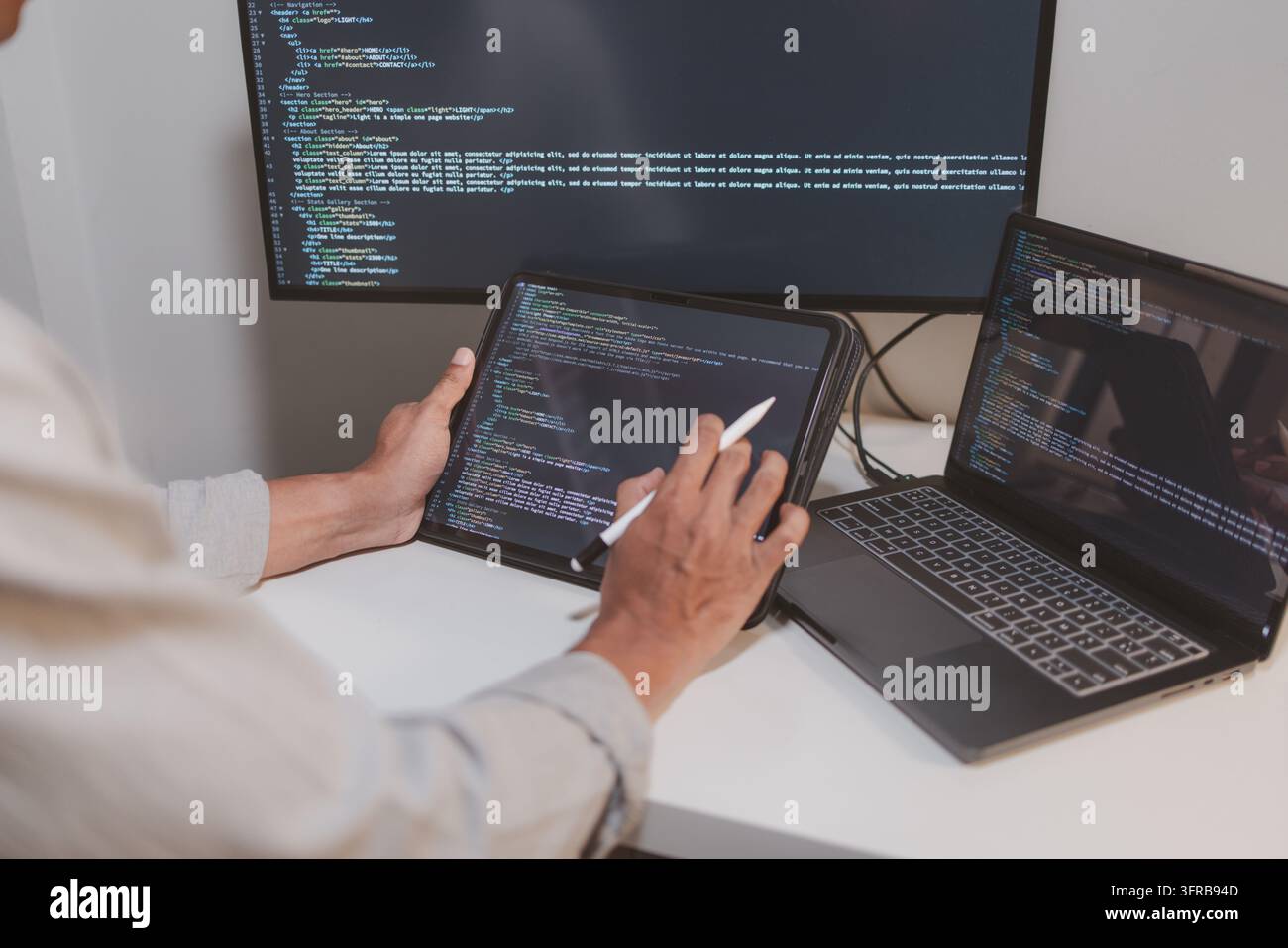 Software engineer using a stylus with a tablet to review source code in a modern workspace. Close-up of programming, code debugging, software developm Stock Photo