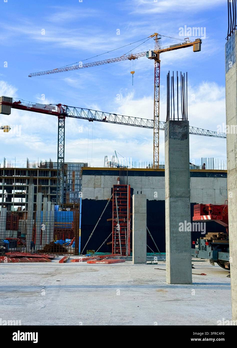 Yellow tower crane and concrete pillars at a residential building construction site. - Smartphone Captured Stock Image