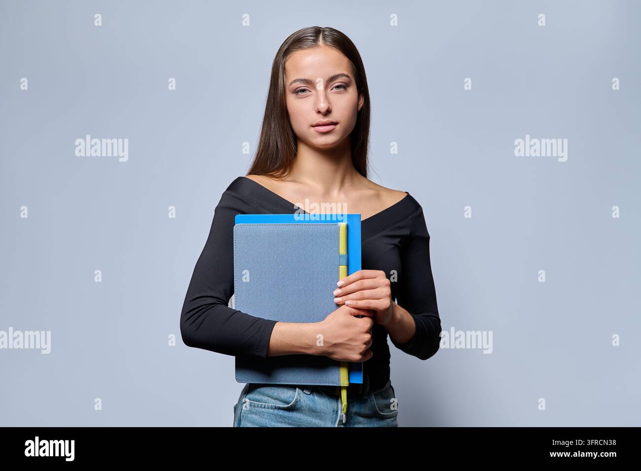 Young female student holding notebook in studio portrait Stock Photo