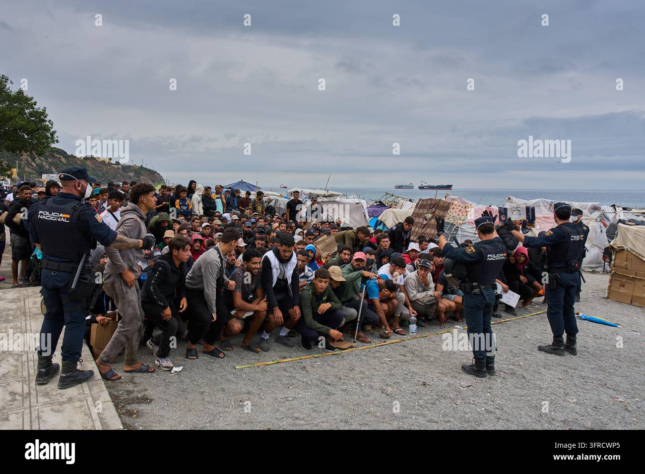 Migrants wait for food distribution to begin on El Trampolín Beach in ...
