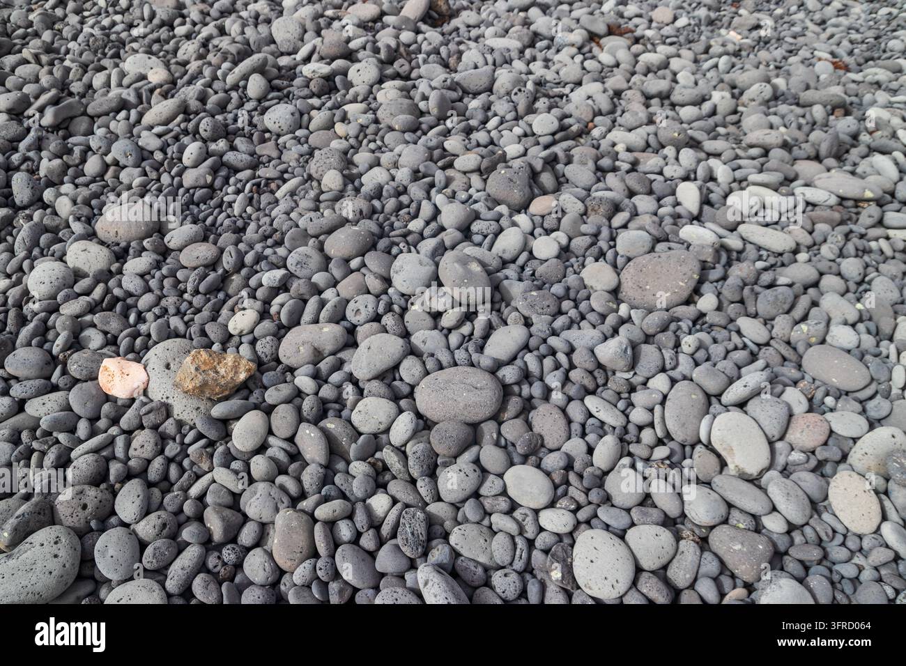 Natural background of smooth grey and black volcanic pebbles on a beach Stock Photo