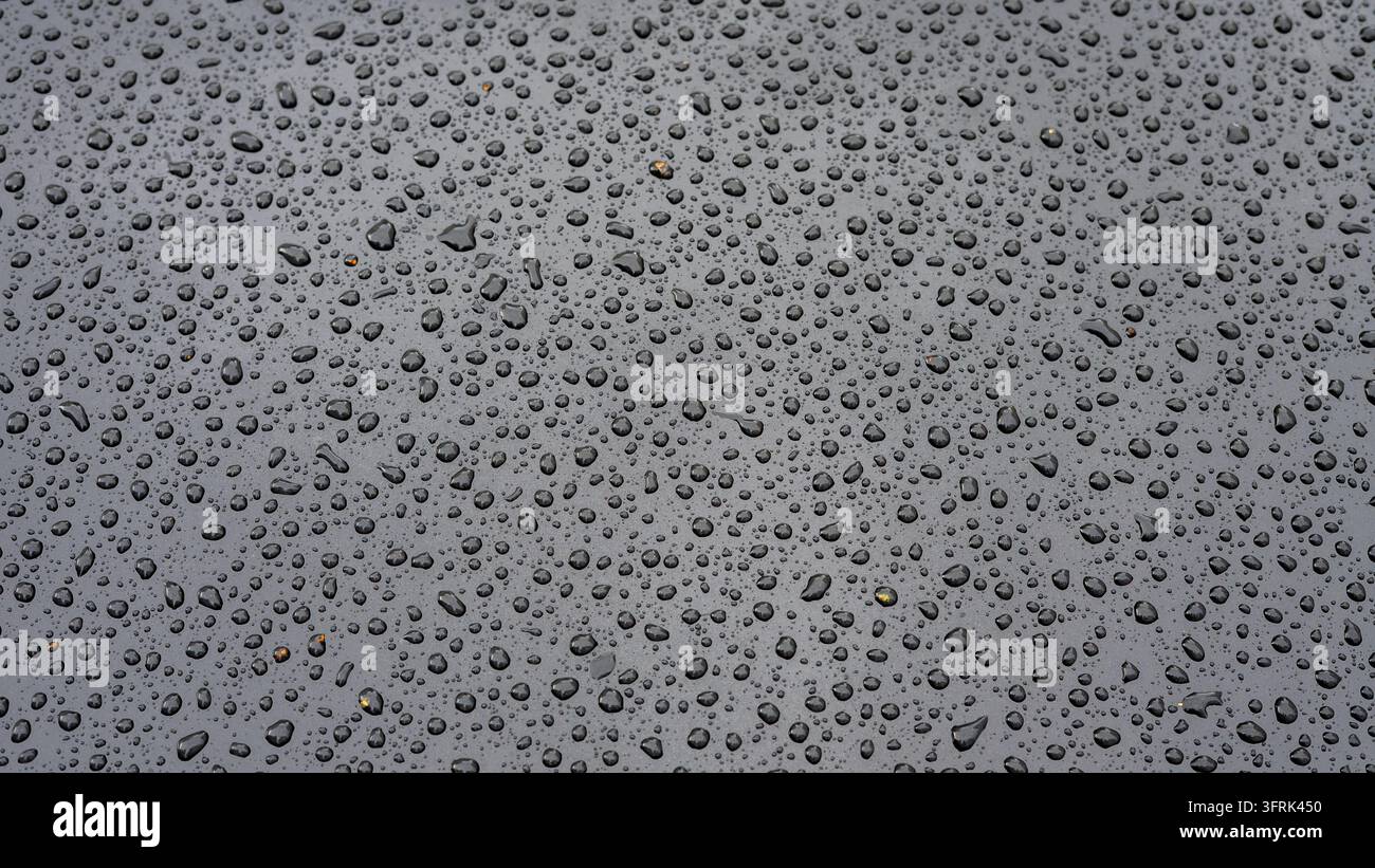 Close-up of a metallic surface covered with water droplets, creating an ...