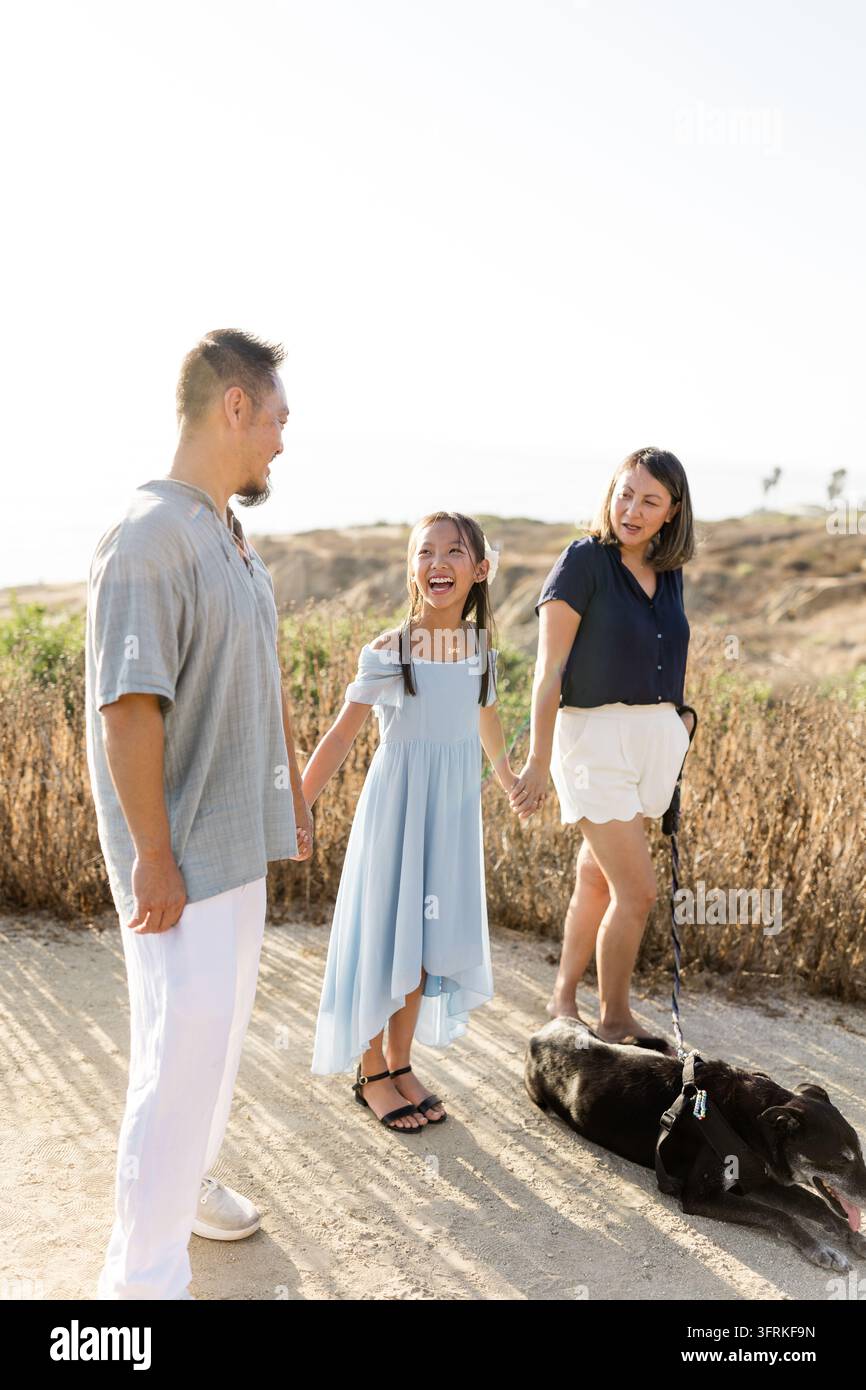 Happy Asian family holding hands on a sunny walk Stock Photo