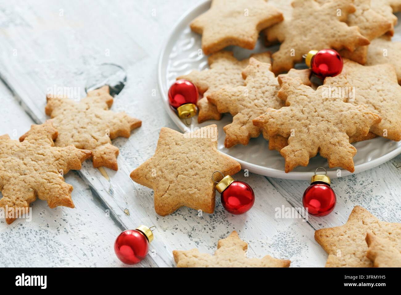 White plate with ginger cookies and red Christmas balls on wooden table, selective focus Stock Photo