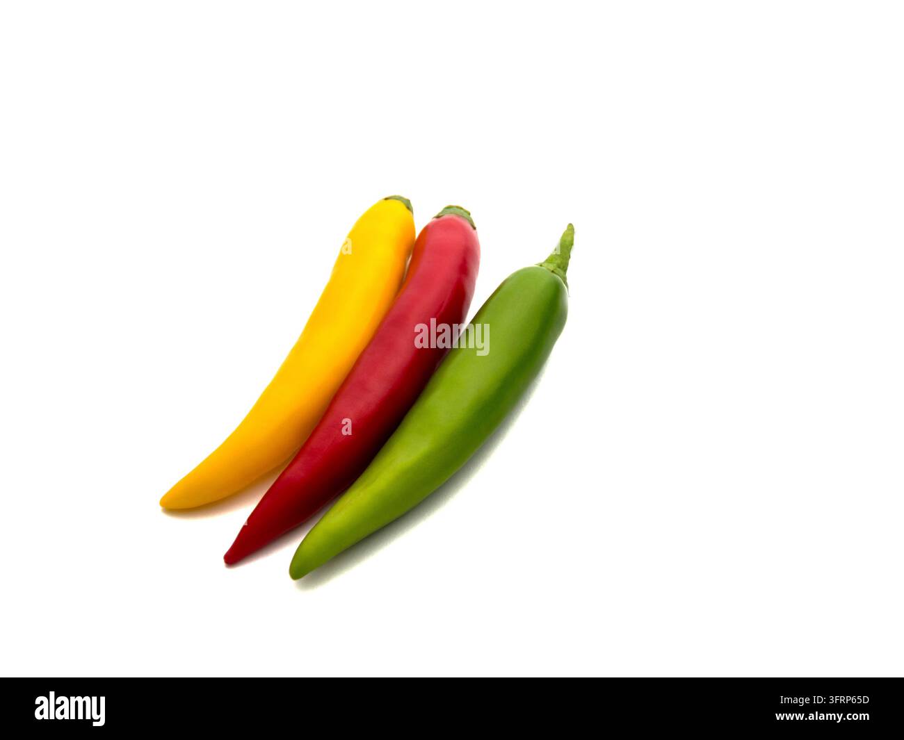 Close-up of three fresh and healthy chili peppers of different colors isolated on white background. Selective focus Stock Photo