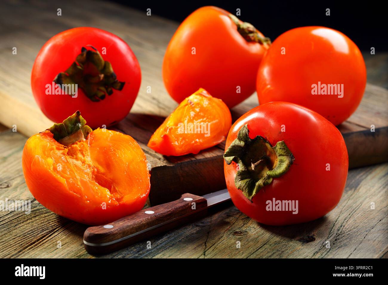Ripe persimmons and knife on a wooden table Stock Photo
