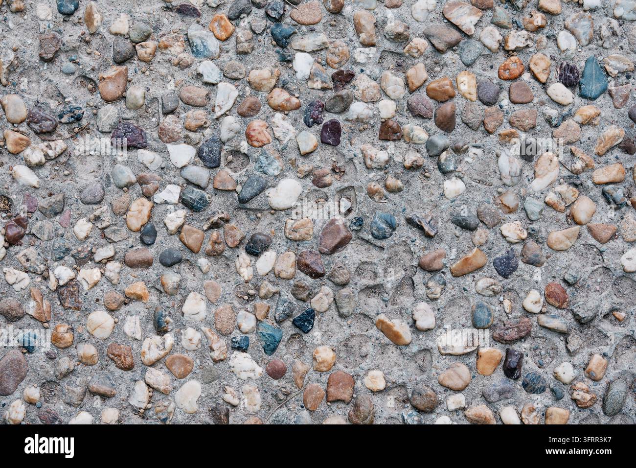 Pebble aggregate concrete surface with mixed stones embedded in cement - texture background. Stock Photo