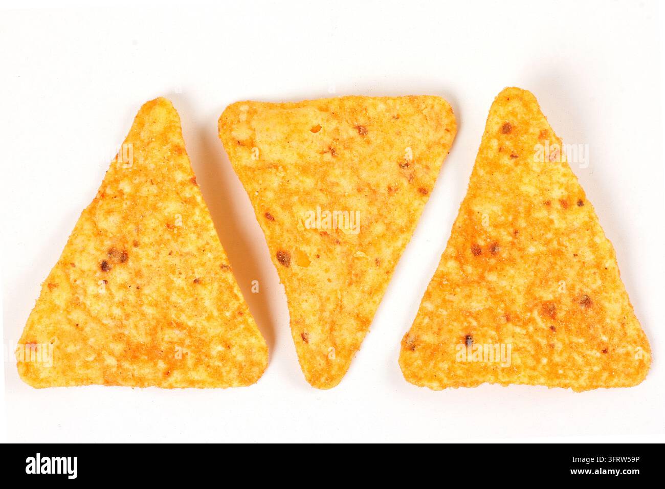 Three crispy baked triangular nacho tortilla chips isolated on a white background. Mexican cuisine. Top view Stock Photo