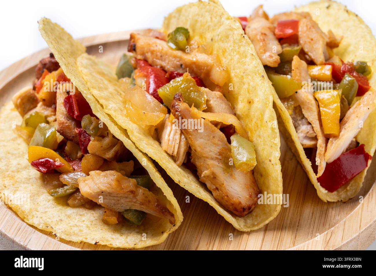 Crispy Mexican chicken tacos with colorful vegetables on white background Stock Photo