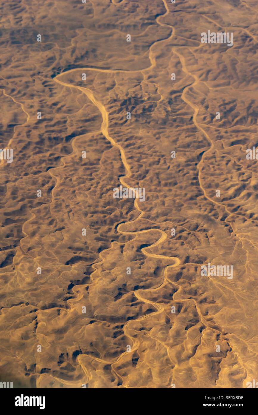 Winding Riger Aerial view of winding dry river channels carved across textured desert ...