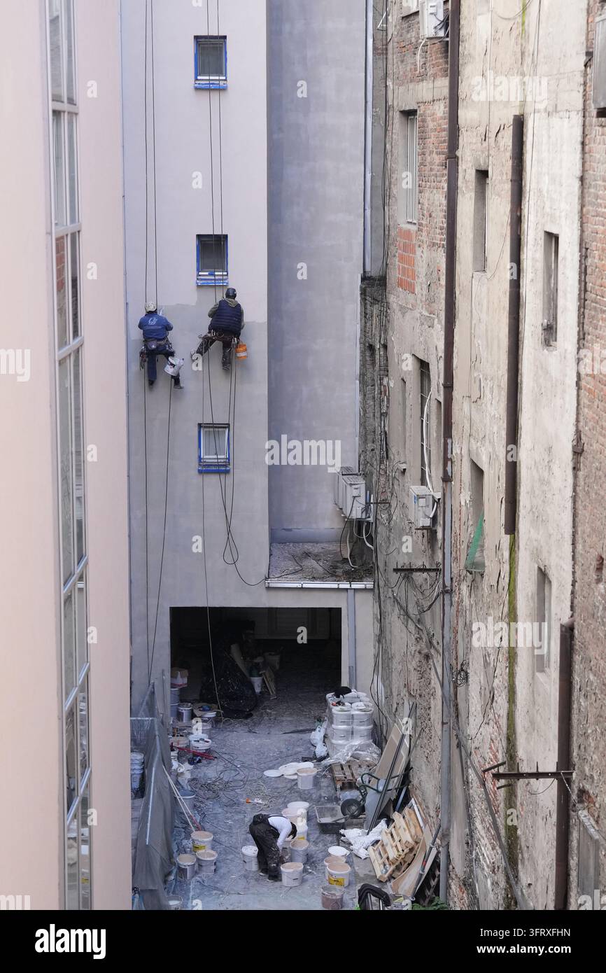 Workers paint the exterior walls of a building in Belgrade, Serbia ...