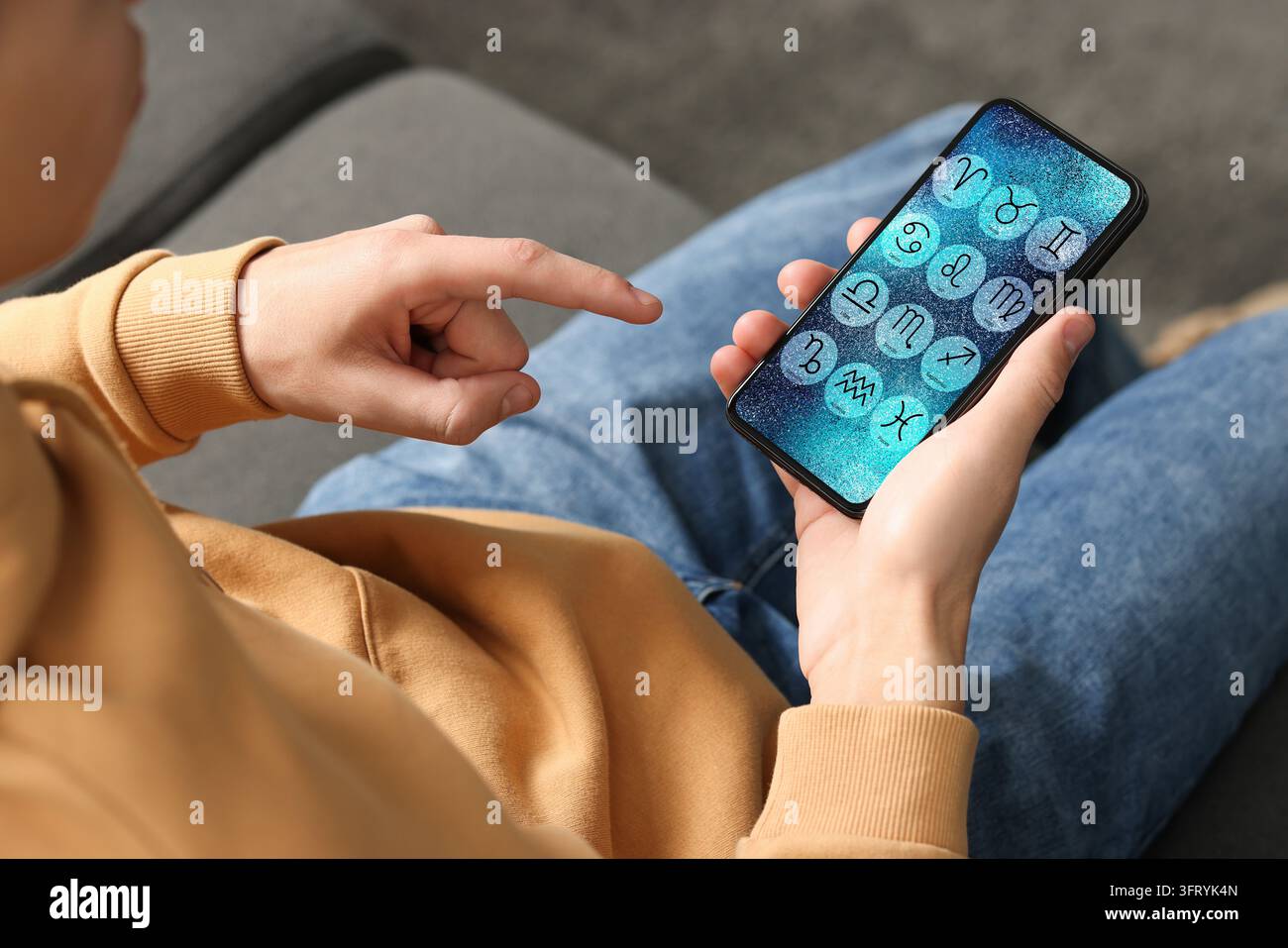 Man using astrology app on his smartphone indoors, closeup Stock Photo