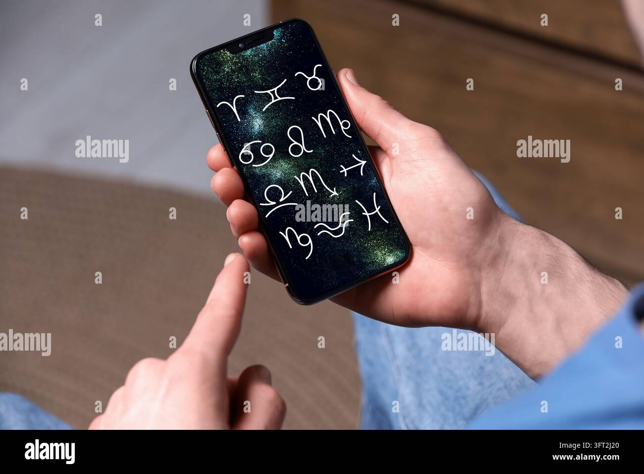 Man using astrology app on his smartphone indoors, closeup Stock Photo