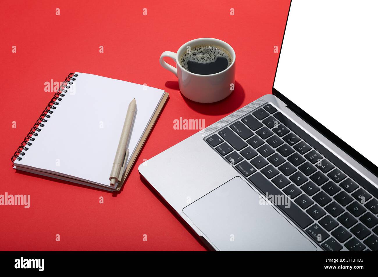 Laptop with blank screen, coffee and notebook with pen on red background Stock Photo