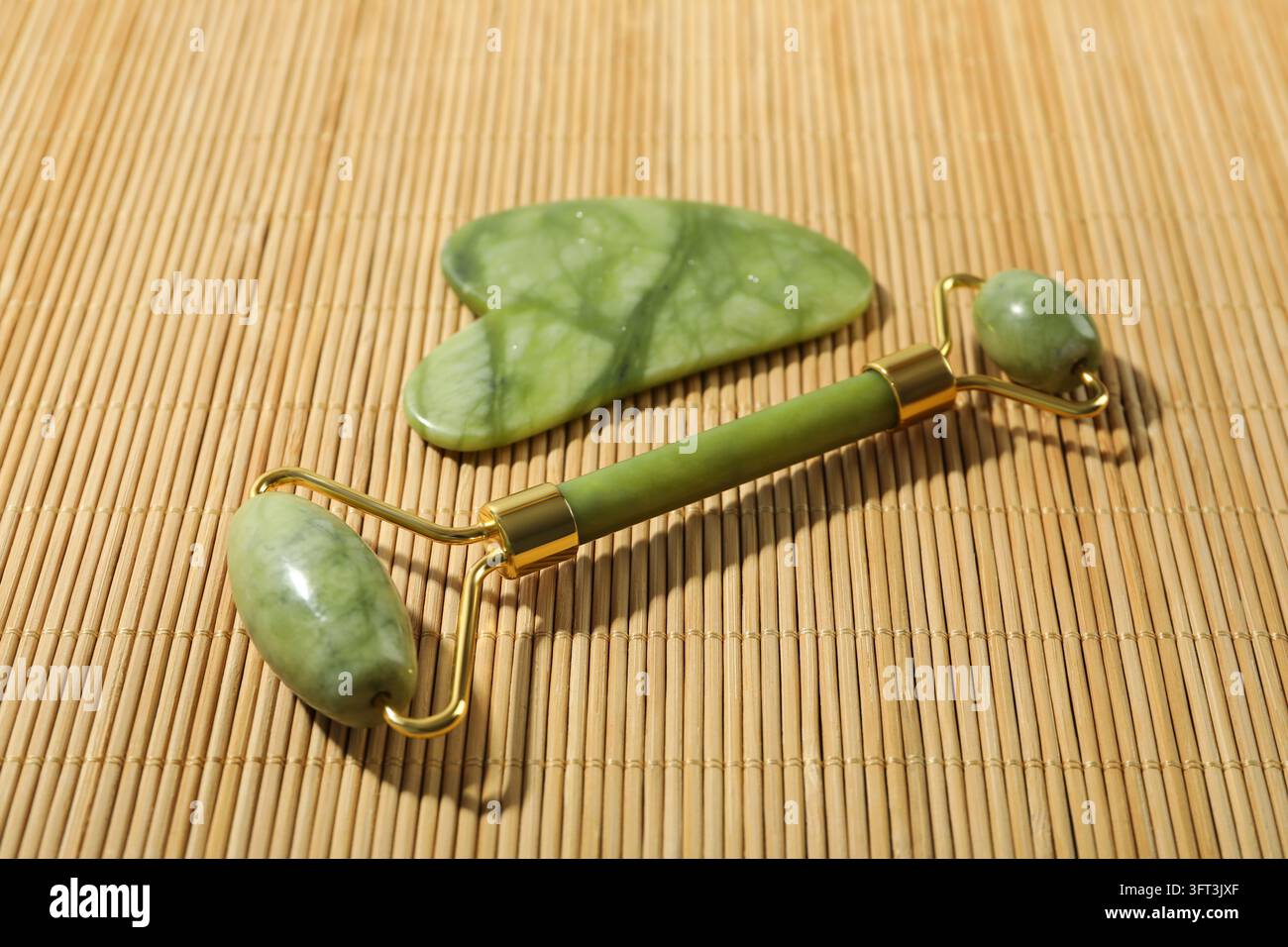 Gua sha and face roller on bamboo background Stock Photo - Alamy