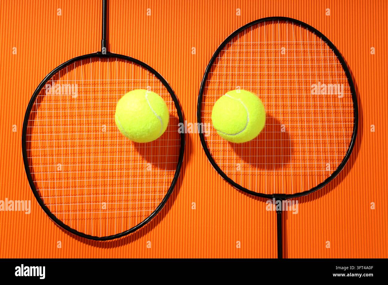 Badminton rackets and tennis balls on textured orange background Stock ...