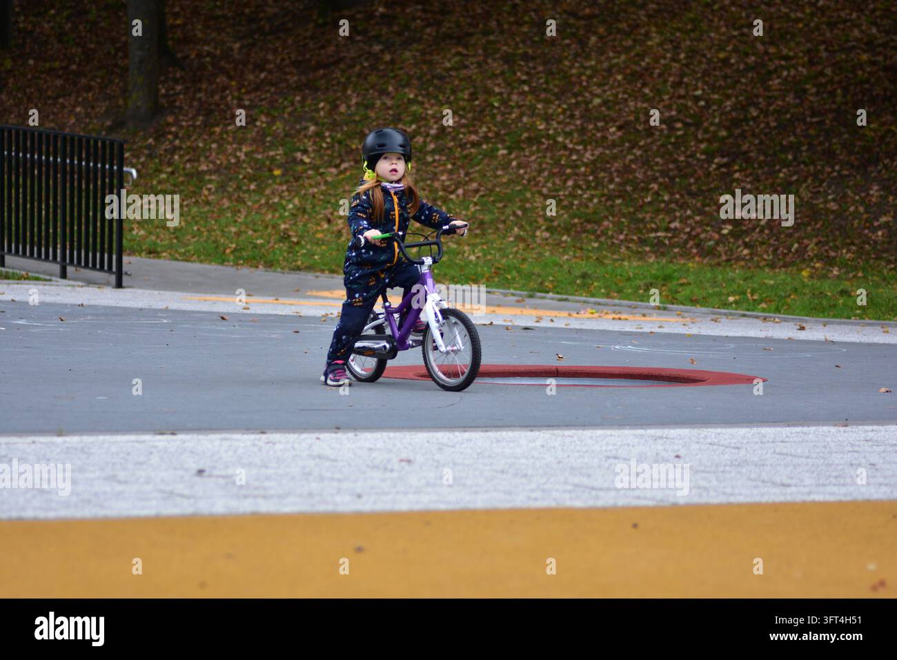 Young girl wearing a safety helmet standing with her small bicycle at ...