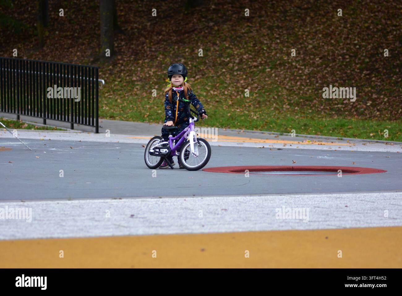 Young girl wearing a safety helmet standing with her small bicycle at ...