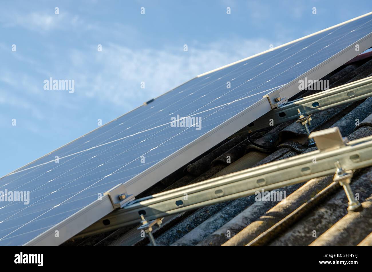 Close up view of photovoltaic modules mounted on a weathered tile roof ...