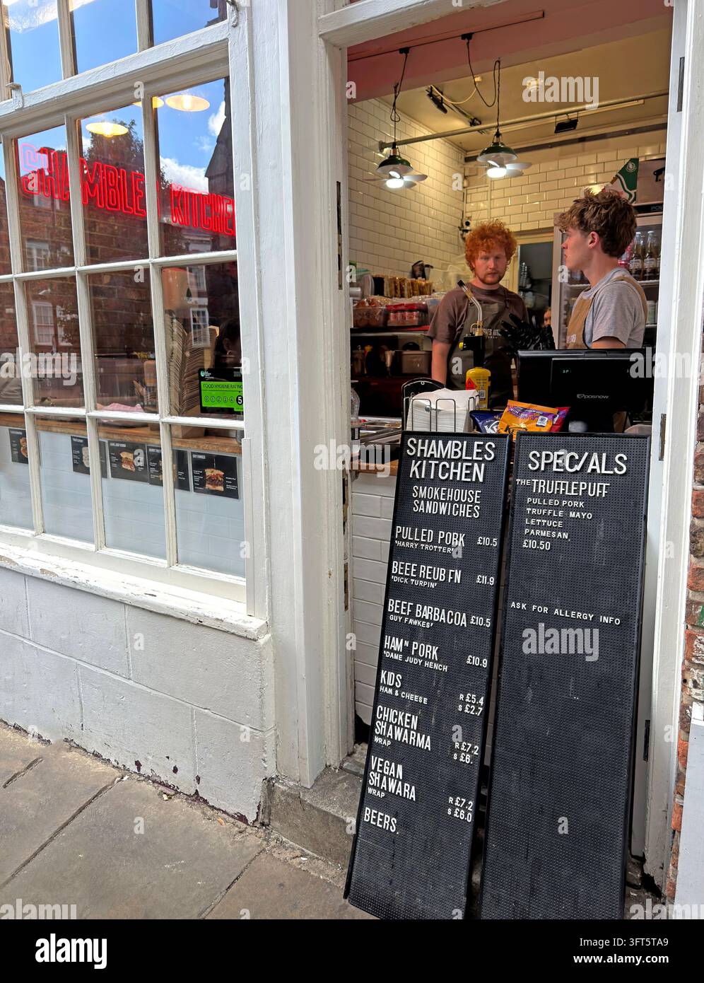 Customer outside a small café and kitchen business on York's historic Shambles. Stock Photo
