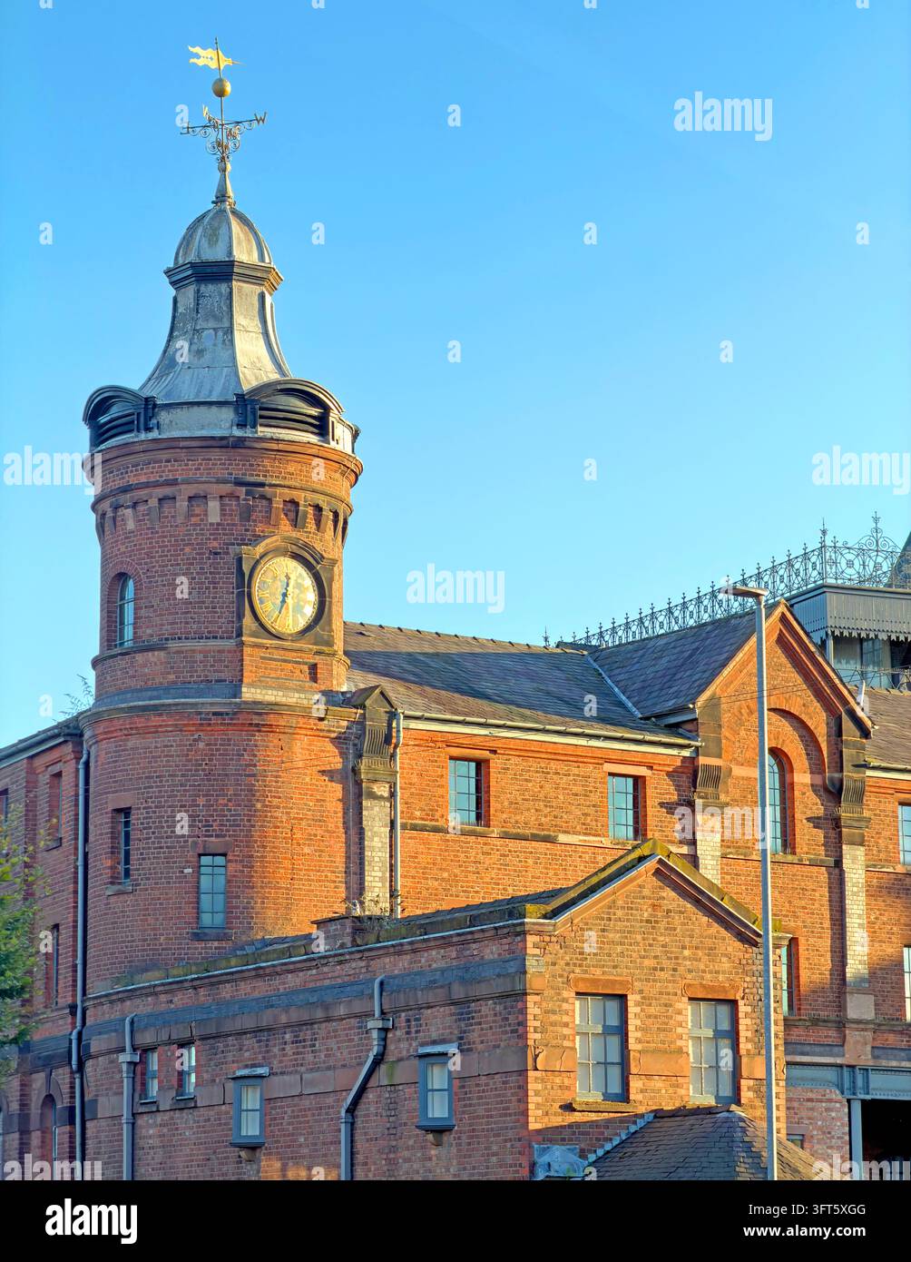 Historic Greenall's brewery clock tower and surviving brick buildings on Wilderspool Causeway in Warrington. Stock Photo