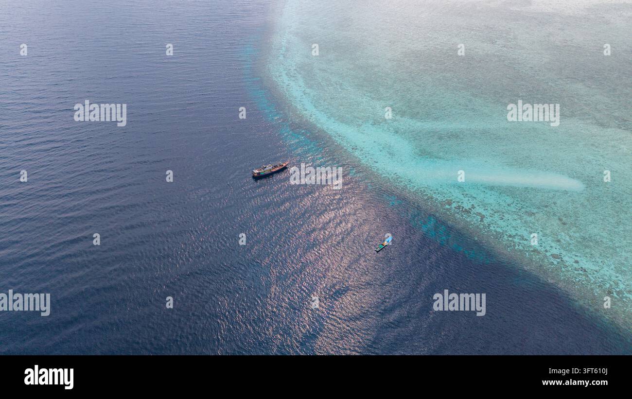 Aerial view of a coral reef drop-off with deep blue water transitioning ...