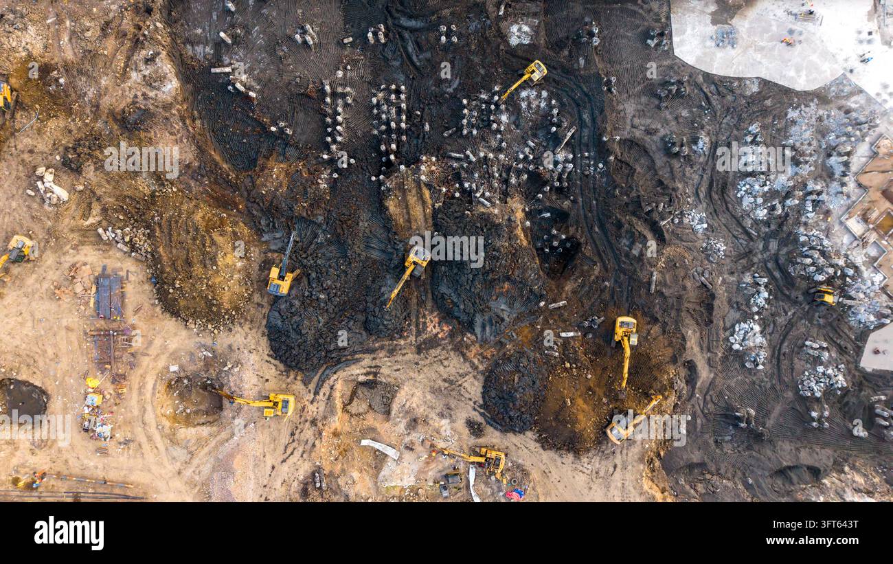 Aerial view of multiple yellow excavators working on a muddy construction site in India. Stock Photo