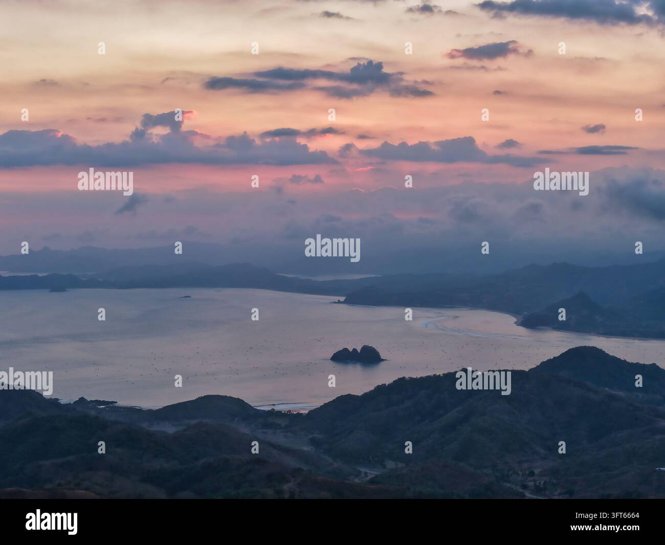 Aerial view of Tampah Beach at sunset with rolling hills, calm bay ...