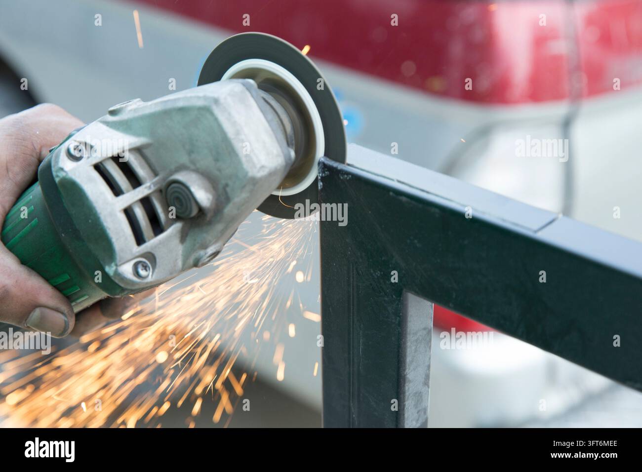 Close up of a worker's hands using an electric angle grinder to cut a ...