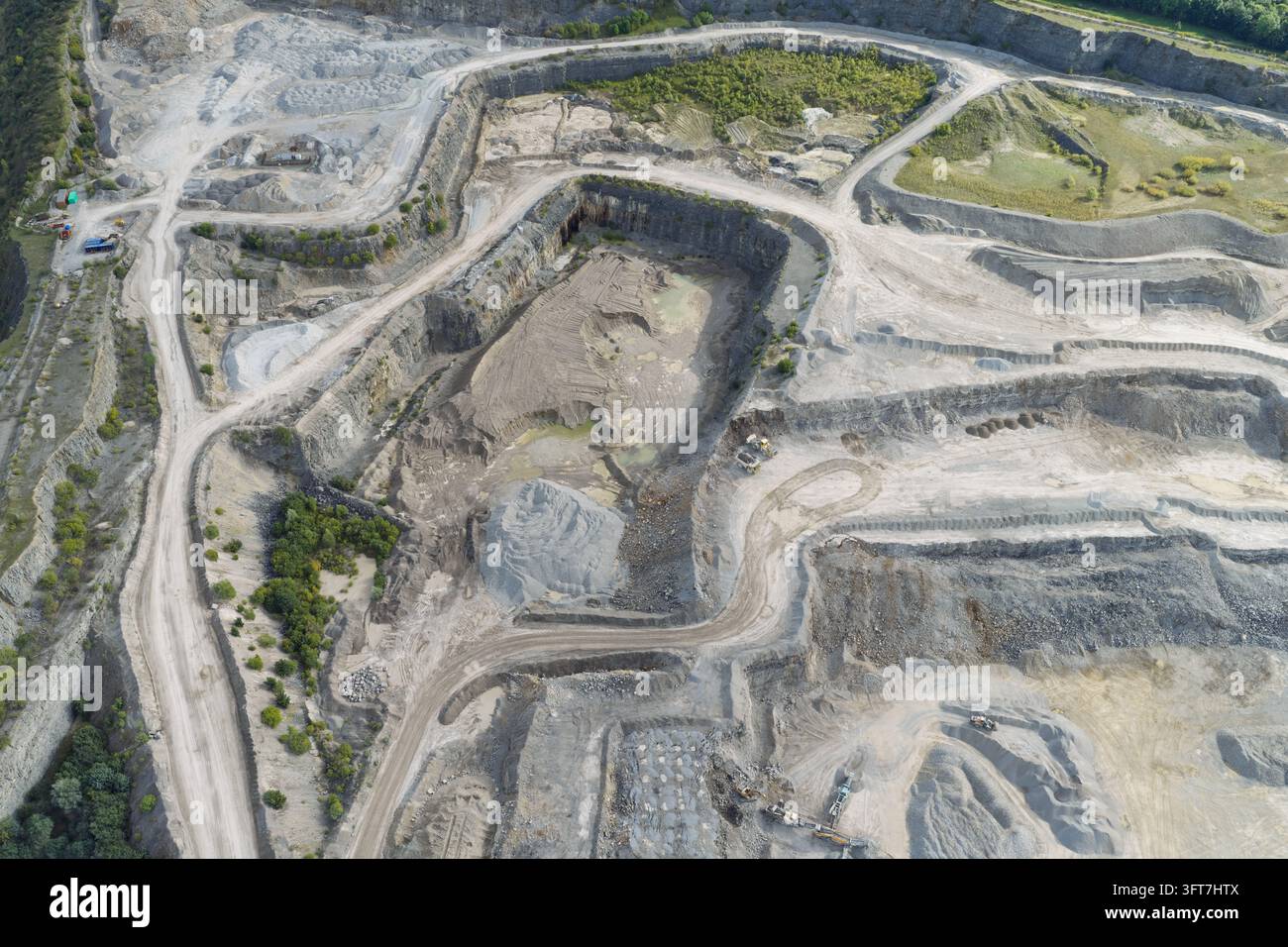 Aerial view of a large open-pit cement quarry with terraced rock walls ...