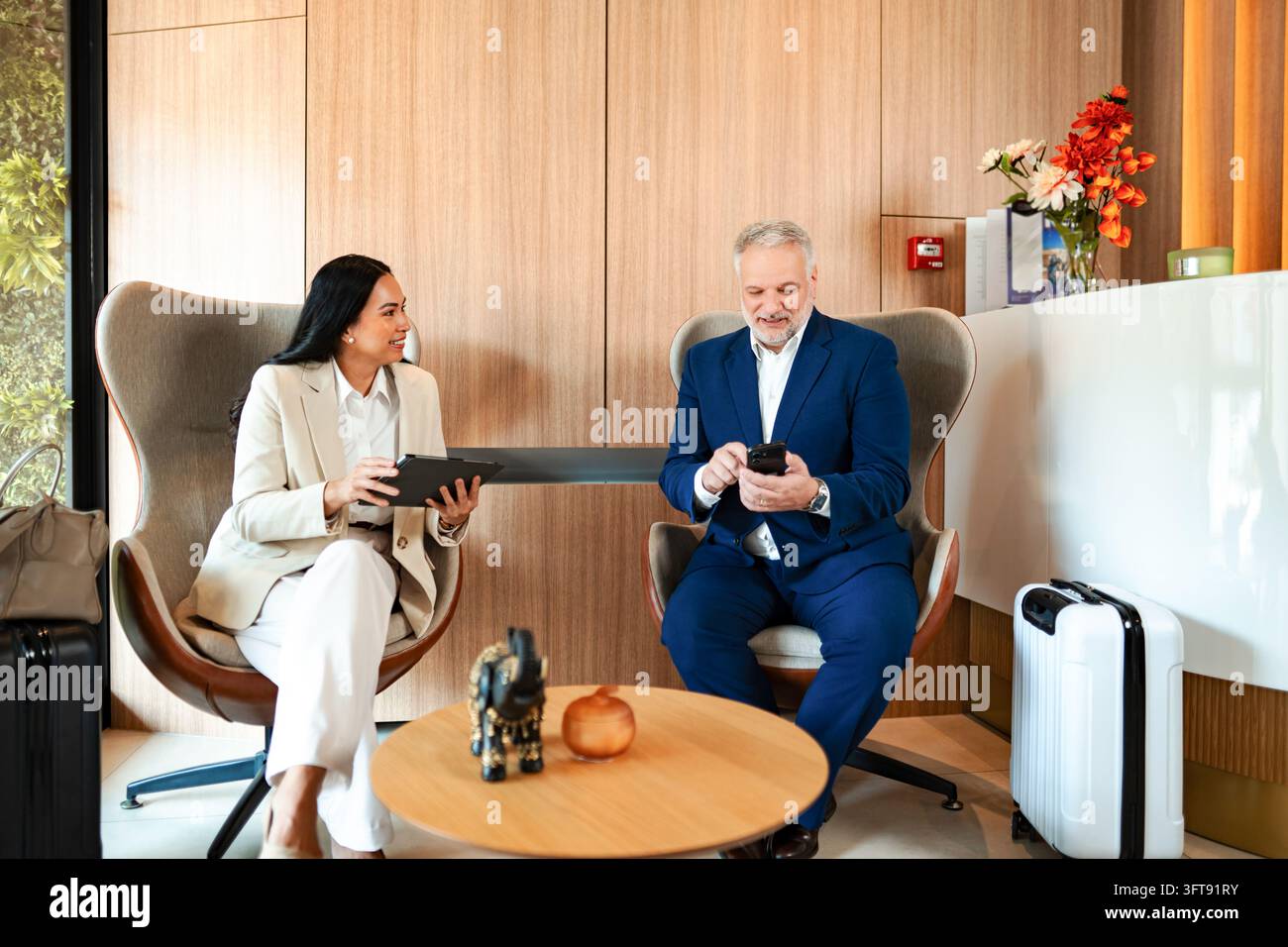 Business travelers waiting in modern hotel lobby area Stock Photo