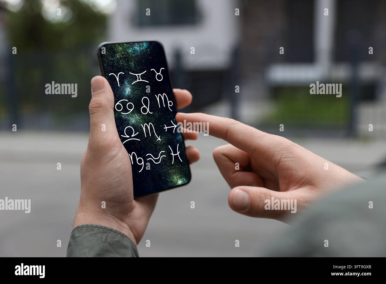 Man using astrology app on his smartphone outdoors, closeup Stock Photo