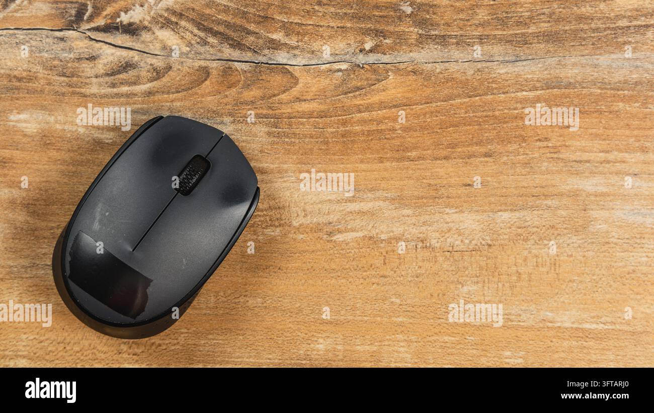A computer mouse sits on a wooden desk in a modern office space. The ...