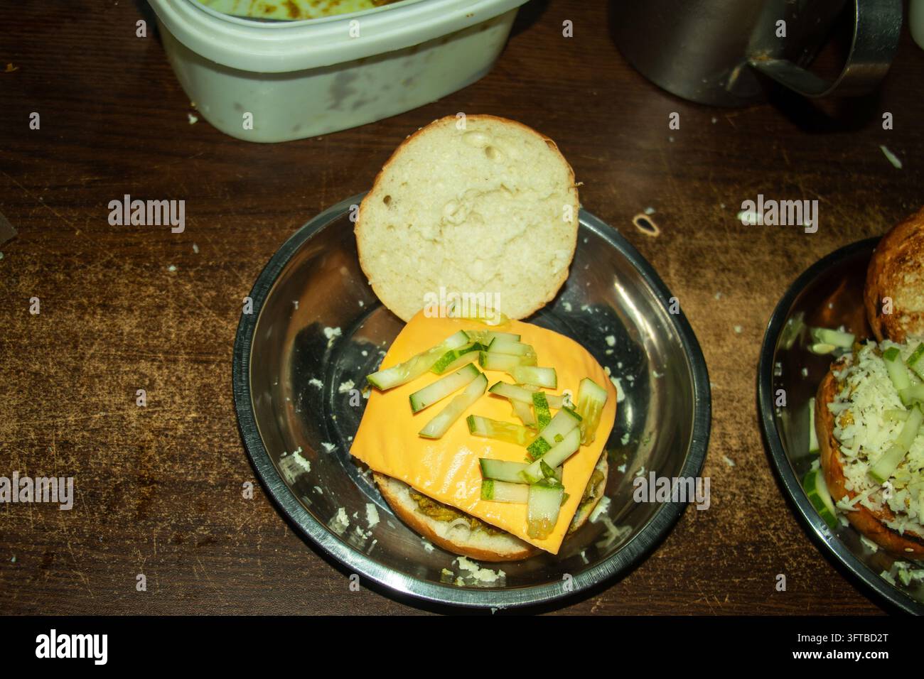 Chicken burger being assembled on metal plate featuring slice of ...