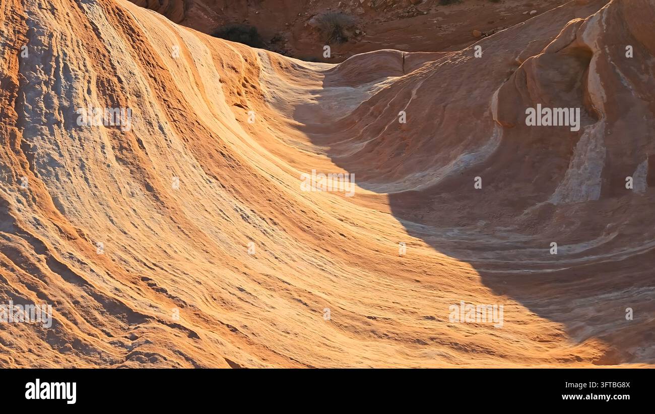 View of the unique sandstone rock formations at Valley of Fire State Park with vibrant orange and white layers illuminated by golden hour light in Moa Stock Photo