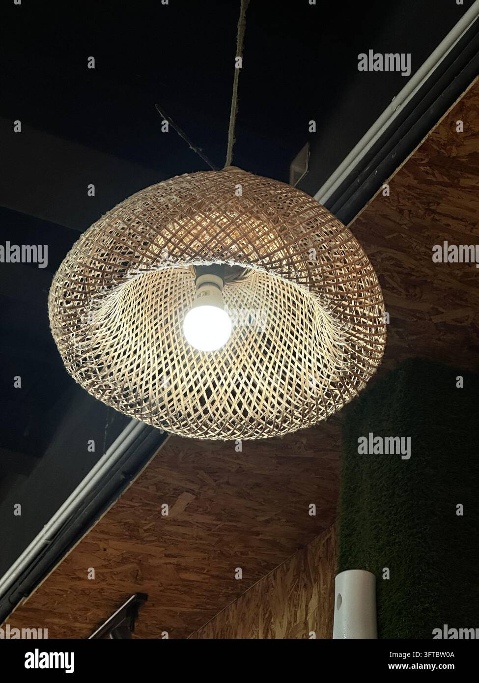 A decorative woven rattan lampshade hanging from the ceiling with a ...