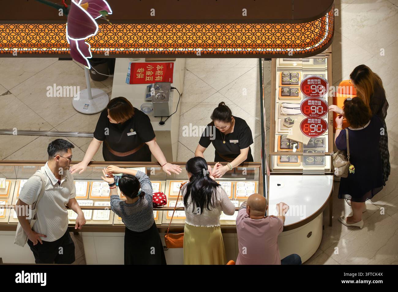 Gold Rong's Customers select gold jewelry at a mall counter in Shanghai, east China ...