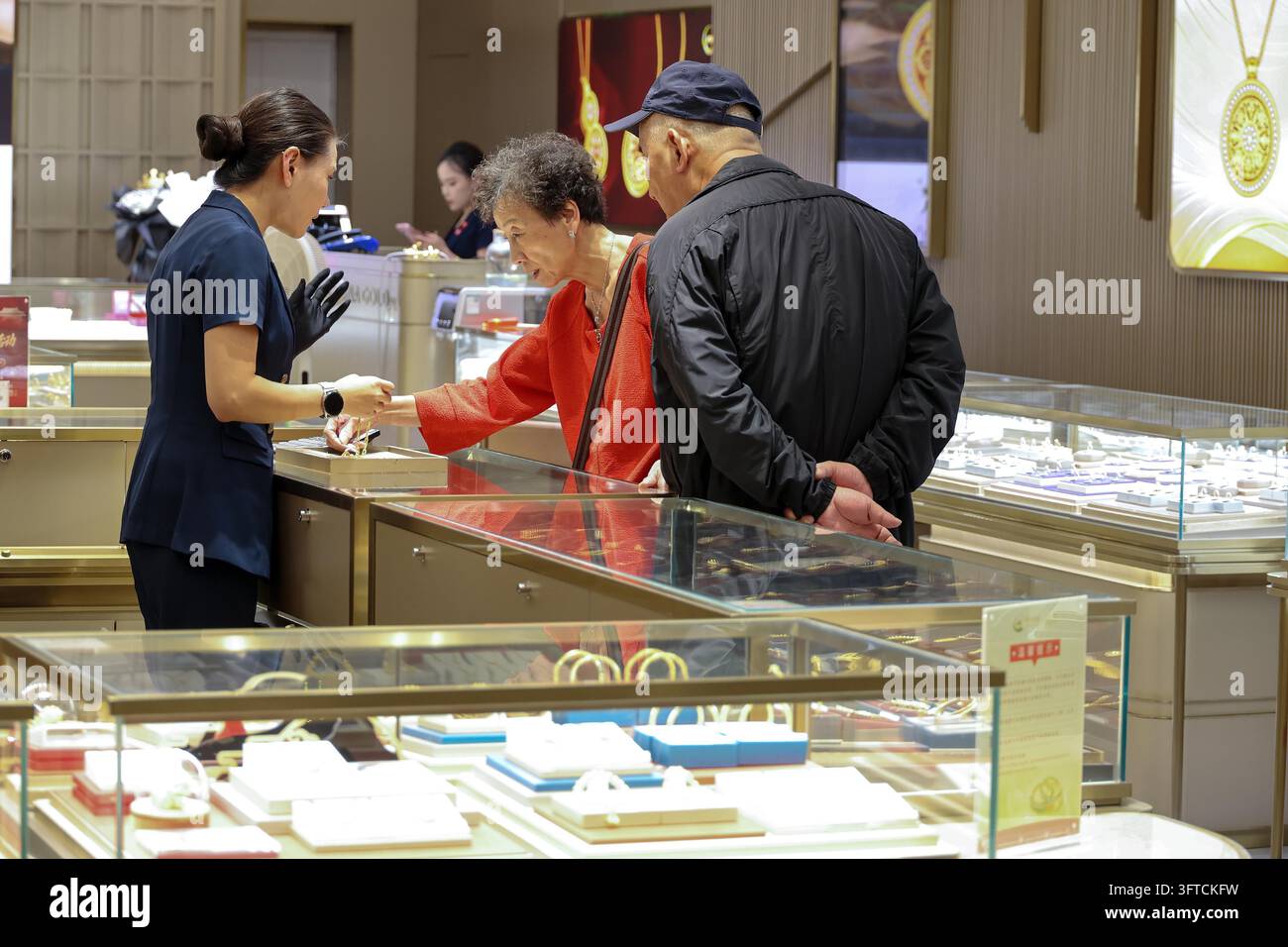 Gold Rong's Customers select gold jewelry at a mall counter in Shanghai, east China ...