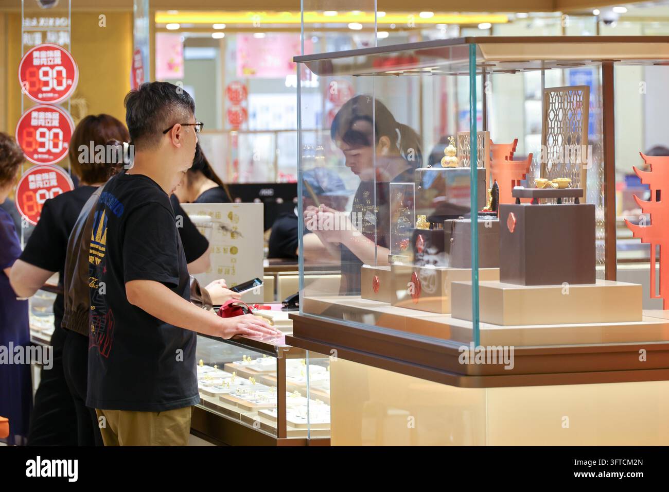 Gold Rong's Customers select gold jewelry at a mall counter in Shanghai, east China ...
