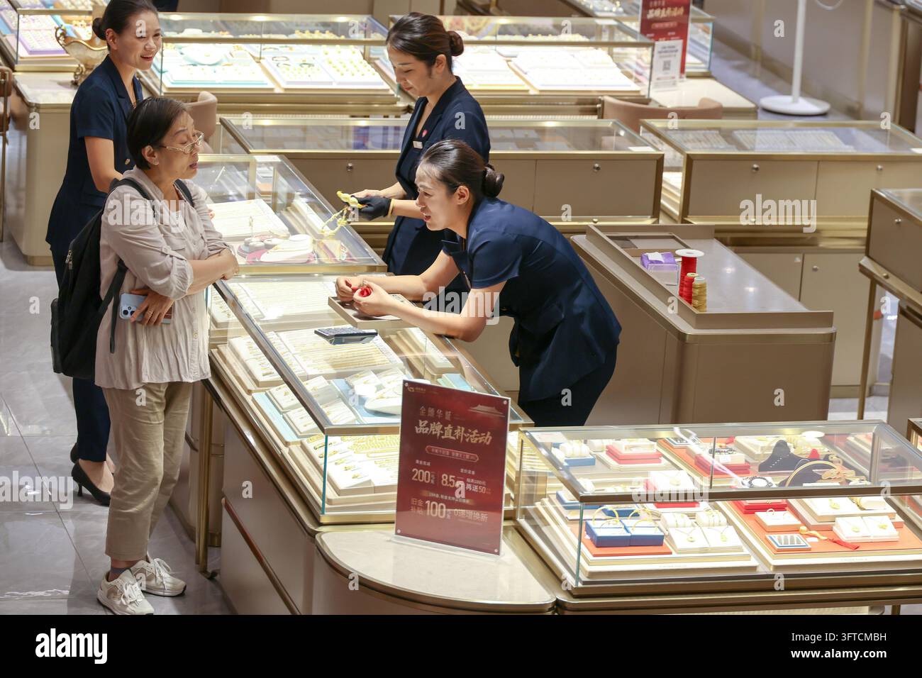Gold Rong's Customers select gold jewelry at a mall counter in Shanghai, east China ...