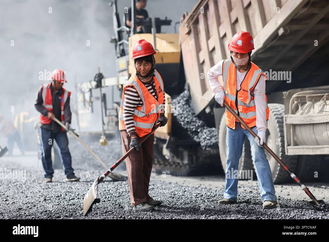 Workers pave an asphalt road at a rapid renovation project site on the ...