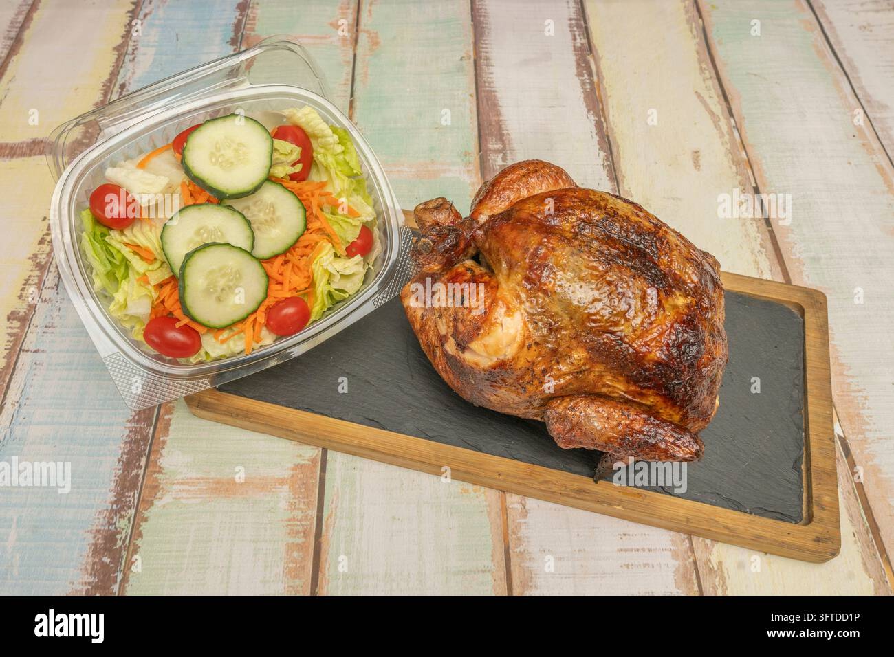 Whole glazed rotisserie chicken on a slate and wood serving board ...