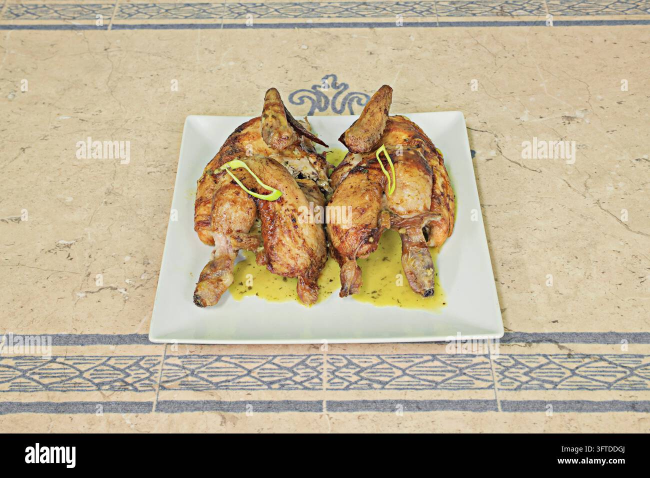 Two roasted chicken halves with bronzed skin, garnished with green ...