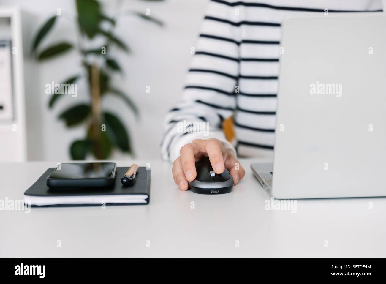 Using The Mouse Close up of young woman hand using computer mouse next to laptop at ...
