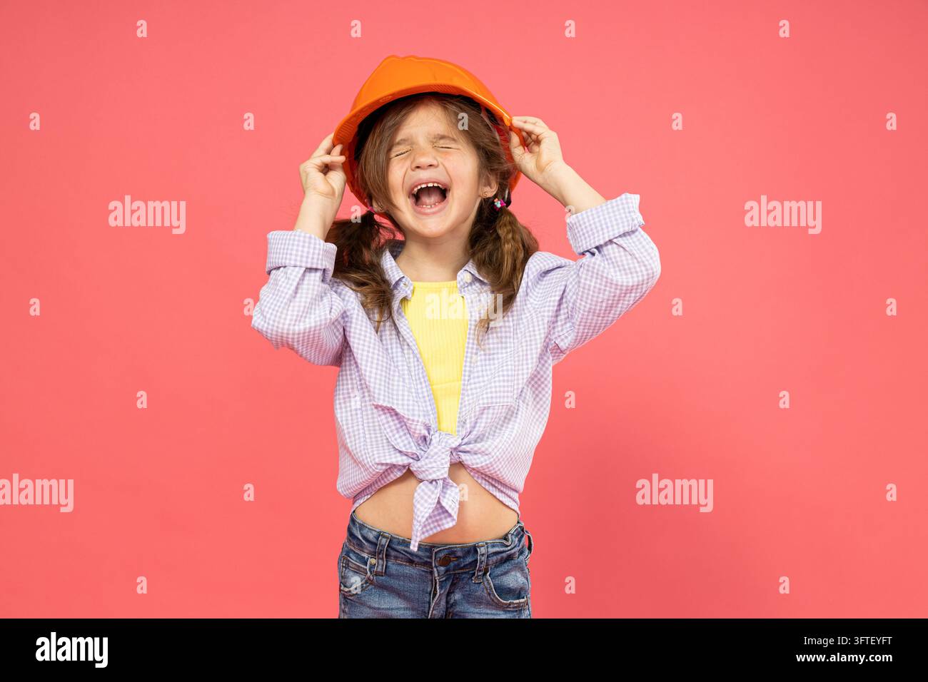 Little girl in construction helmet on pink background Stock Photo - Alamy