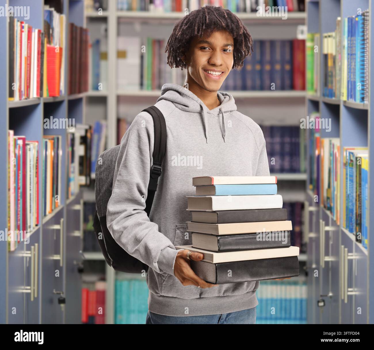 Smiling male african american student with a backpack holding a pile of ...