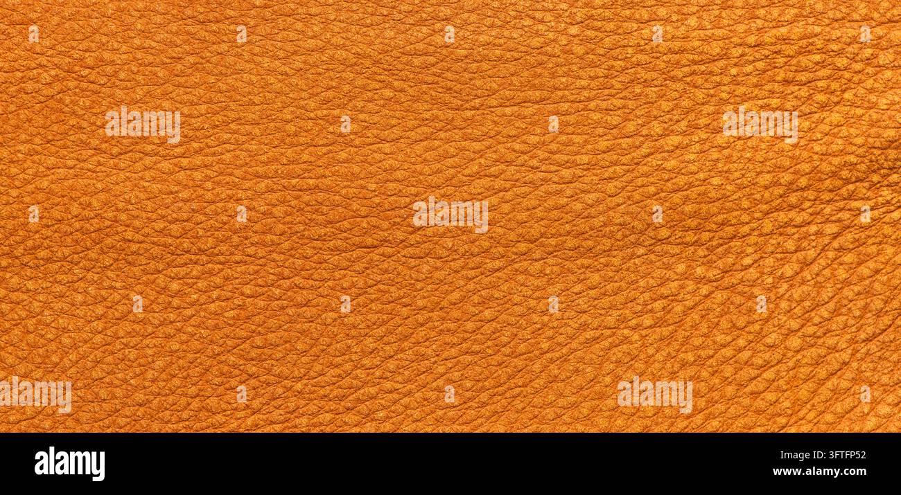 Close-up of a warm orange-yellow leather texture featuring a fine pebble grain pattern and a soft matte finish, offering a natural and rustic aestheti Stock Photo