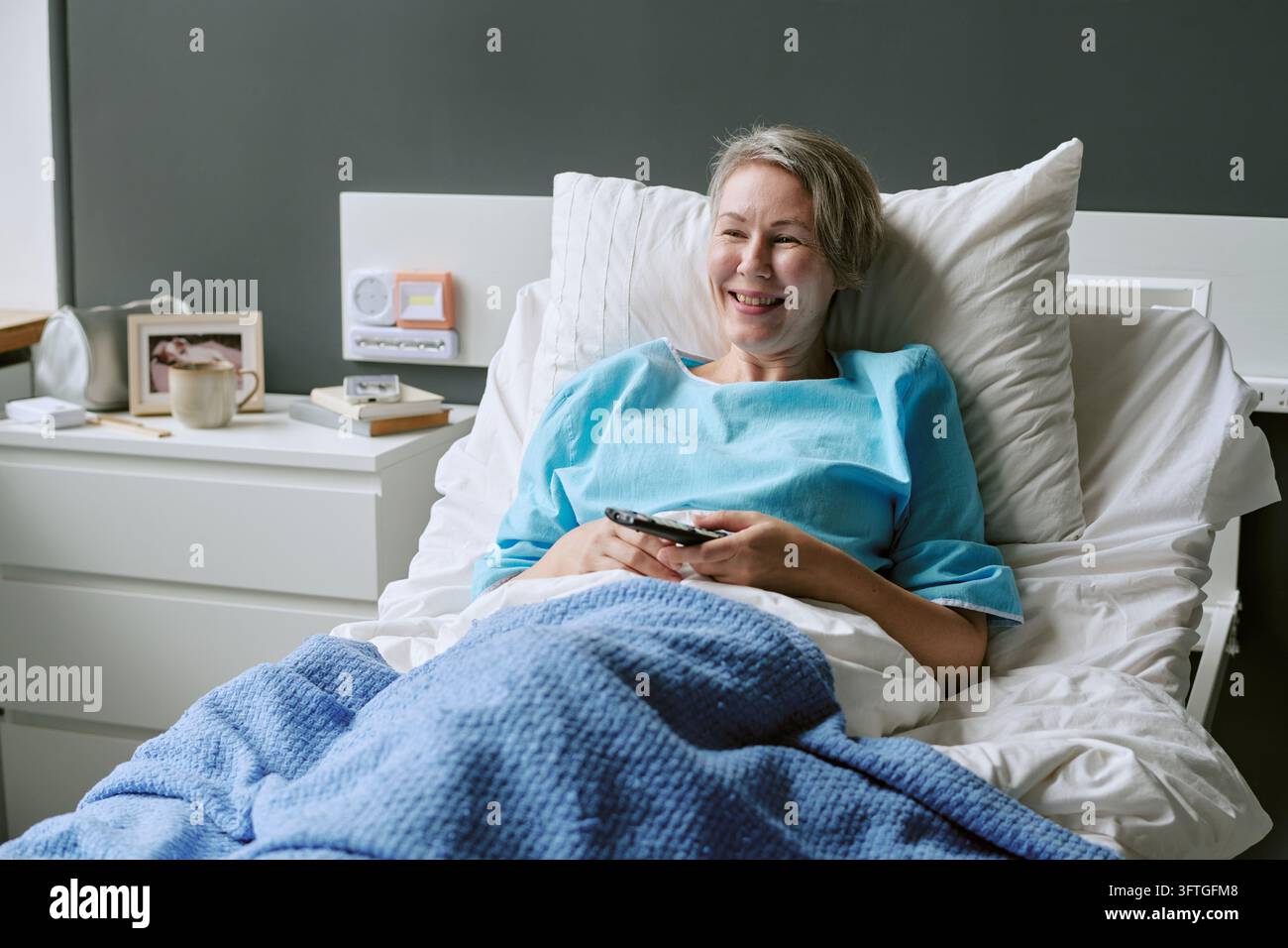 Middle Aged Woman Smiling While Holding Remote Control in Hospital Bed ...